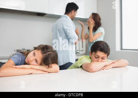 Les jeunes enfants tandis que triste parents quarreling in kitchen Banque D'Images