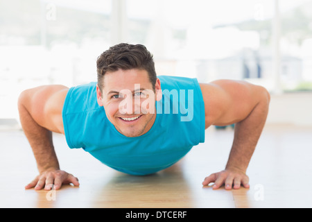 Portrait of a smiling young man doing push ups Banque D'Images