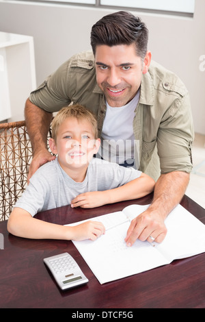 Cheerful père fils aidant à faire ses devoirs de mathématiques à table Banque D'Images