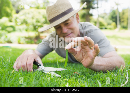 L'homme coupé de l'herbe avec des ciseaux Banque D'Images