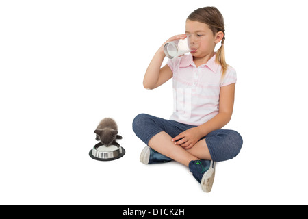 Jolie fille et de chaton gris à la fois la consommation de lait Banque D'Images