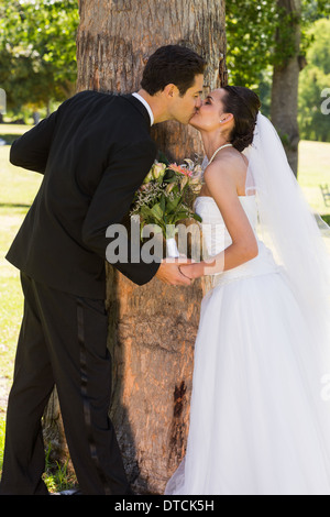 Romantic newlywed couple kissing in park Banque D'Images