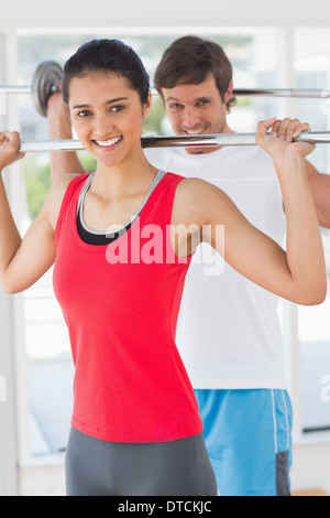 Fit young man and woman lifting barbells Banque D'Images