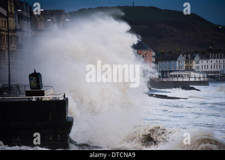 Pays de Galles Aberystwyth UK, samedi 15 Fen 2014 rafales de vent jusqu'à 70 mph drive énormes vagues battant contre le mur de la mer et de la promenade à Aberystwyth, sur la côte ouest du pays de Galles de l'UK à marée haute première chose ce matin. Après des mois de coups de vent violents et puissants raz de marée, des vents forts d'aujourd'hui sont appelées à être la dernière sur la séquence en cours de tempêtes. Le temps se calme, bien que la pluie, est prévue pour les prochains jours. Credit : Keith morris/Alamy Live News Banque D'Images