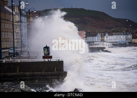 Pays de Galles Aberystwyth UK, samedi 15 Fen 2014 rafales de vent jusqu'à 70 mph drive énormes vagues battant contre le mur de la mer et de la promenade à Aberystwyth, sur la côte ouest du pays de Galles de l'UK à marée haute première chose ce matin. Après des mois de coups de vent violents et puissants raz de marée, des vents forts d'aujourd'hui sont appelées à être la dernière sur la séquence en cours de tempêtes. Le temps se calme, bien que la pluie, est prévue pour les prochains jours. Credit : Keith morris/Alamy Live News Banque D'Images