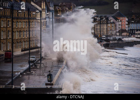 Pays de Galles Aberystwyth UK, samedi 15 Fen 2014 rafales de vent jusqu'à 70 mph drive énormes vagues battant contre le mur de la mer et de la promenade à Aberystwyth, sur la côte ouest du pays de Galles de l'UK à marée haute première chose ce matin. Après des mois de coups de vent violents et puissants raz de marée, des vents forts d'aujourd'hui sont appelées à être la dernière sur la séquence en cours de tempêtes. Le temps se calme, bien que la pluie, est prévue pour les prochains jours. Credit : Keith morris/Alamy Live News Banque D'Images