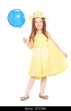 Portrait d'une adorable petite fille en robe jaune tenant un ballon bleu Banque D'Images