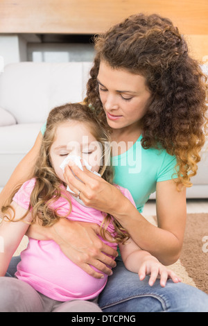 Mère attentive à aider sa petite fille souffler son nez Banque D'Images