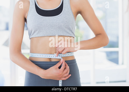 Mid section of a woman measuring waist in fitness studio Banque D'Images