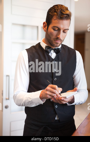 Handsome waiter prendre une commande Banque D'Images