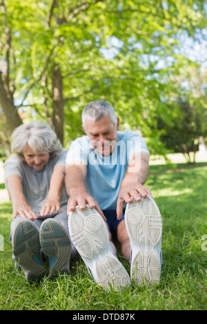 D'âge mûr qui s'étend les mains pour les jambes du park Banque D'Images