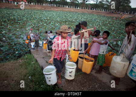 Un homme remplir les contenants avec de l'eau dans un petit lac à Dala Township, Myanmar, le lundi 6 mai 2013 Banque D'Images