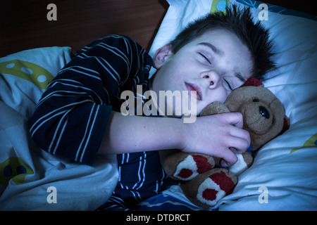 Enfant endormi avec son ours en peluche. Banque D'Images