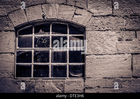 Fenêtre ancienne dans un cottage en pierre avec un trou de balle dans le verre Banque D'Images