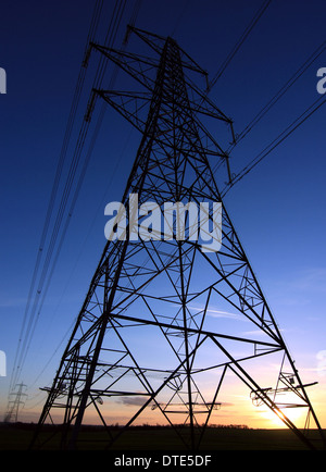 Un grand pylône d'électricité silhouetted against a sunset dans le Cambridgeshire campagne. Banque D'Images