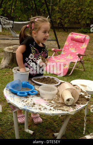 Petite fille jouant avec du sable sur la table de jardin Banque D'Images