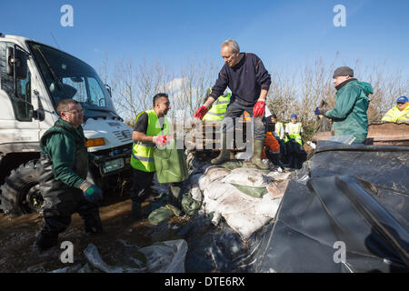 Des bénévoles de l'organisation de l'aide du khalsa se rencontrer avec le personnel de l'Agence de l'Environnement le 16 février, 2014 dans le village de la lande. Les villageois isolés par les inondations recevoir la fourniture d'huile à chauffage stocké dans le bidon. Après des semaines de forte pluie les rivières Parrett et le ton ont de déborder les inondations la plupart des maisons dans le village. C'est la pire inondation de l'histoire vivante. Banque D'Images