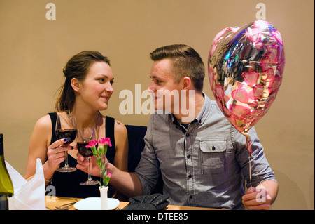 Jeune couple avec ballon en forme de coeur saint Valentin romantique bénéficiant d''un emplacement calme dans un restaurant de nuit Banque D'Images