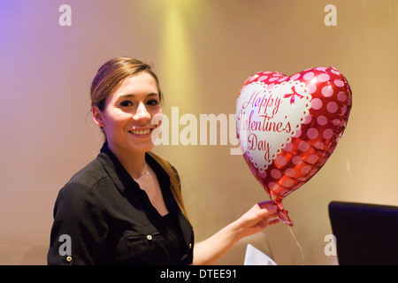 Jeune femme avec ballon en forme de coeur saint Valentin romantique bénéficiant d''un emplacement calme dans un restaurant de nuit Banque D'Images