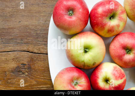 Beaucoup de pomme rouge sur plaque blanche sur table en bois vintage Banque D'Images