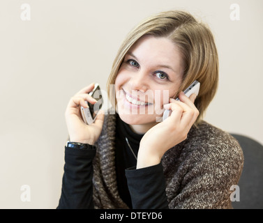 Portrait of smiling beautiful young woman close up avec deux téléphones mobiles Banque D'Images