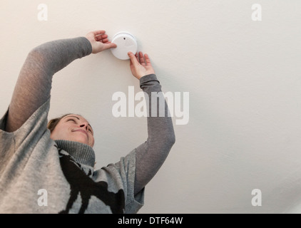 Berlin, Allemagne, une femme recueille un détecteur de fumée au plafond Banque D'Images
