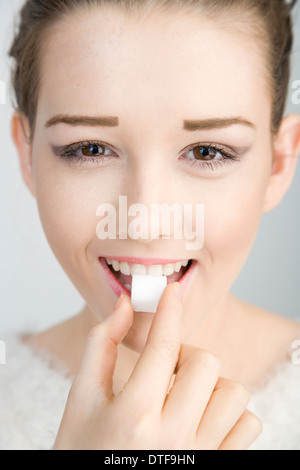 Un joli teenage girl holding un morceau de sucre à la bouche. Banque D'Images