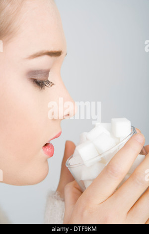 Une jeune femme à la recherche vers le bas dans un verre rempli de cubes de sucre. Banque D'Images