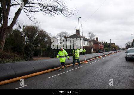 Chertsey Surrey, UK. 17 février 2014. Les agents de l'Agence de l'environnement marche le long d'une barrière contre les inondations rempli d'eau appelé la saucisse comme le des opérations de nettoyage est en cours pour aider les communautés frappées par des inondations le long de la Tamise Crédit : amer ghazzal/Alamy Live News Banque D'Images