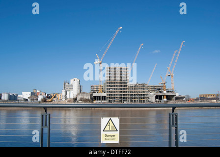 Vue sur la Tamise à partir de battersea atteindre vers un chantier avec des grues, signe de danger eau profonde en premier plan Banque D'Images