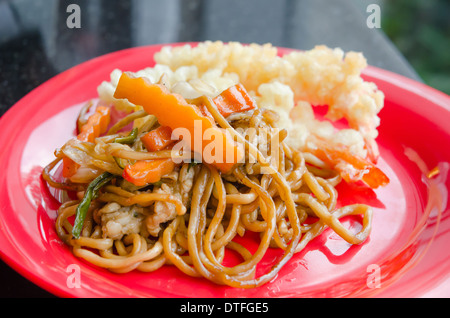 Nouilles sautées avec légumes sur le plat rouge Banque D'Images