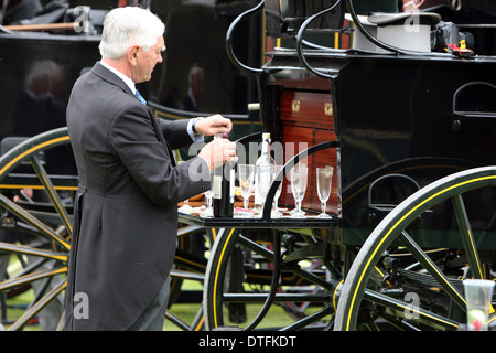 Ascot, Royaume-Uni, élégamment vêtue homme donne à un transport d'un vin mousseux Banque D'Images