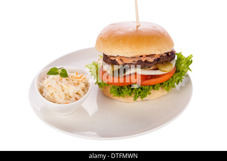 Savoureuse traditionnelle cheeseburger avec un sol recouvert de patty de boeuf fromage fondu et servi avec des rondelles d'oignon, tomate et laitue frisée sur un morceau de pain blanc rond, vue en gros Banque D'Images