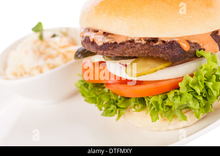 Savoureuse traditionnelle cheeseburger avec un sol recouvert de patty de boeuf fromage fondu et servi avec des rondelles d'oignon, tomate et laitue frisée sur un morceau de pain blanc rond, vue en gros Banque D'Images