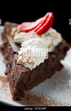 Closeup shot d'un délicieux gâteau au chocolat avec crème et garniture fraises, saupoudrée de cannelle Banque D'Images