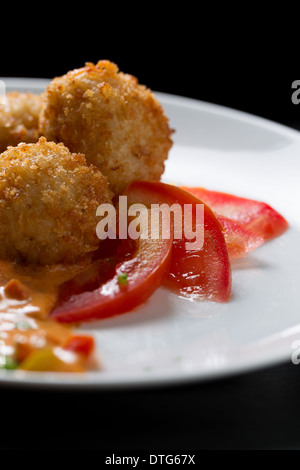 Plat de boulettes de riz Frites enrobées de chapelure, Arancini, avec les tranches de tomate on white plate Banque D'Images