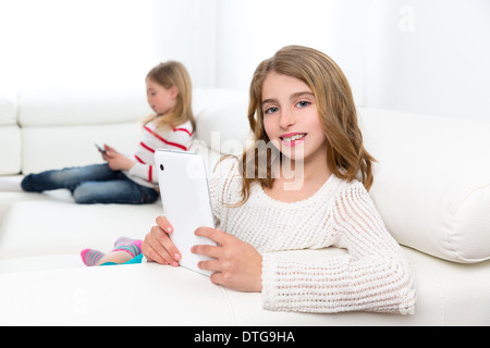 Les enfants d'amis sœur kid girls Playing with tablet pc sur canapé blanc Banque D'Images