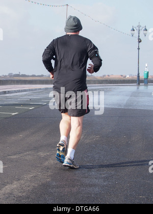 Un homme le jogging le long d'un front de mer de Southsea humide et venteux Banque D'Images