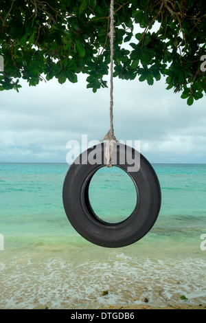 Une vieille balançoire pneu dans le Pacifique Sud se bloque à partir d'un arbre sur une belle plage tropicale. Banque D'Images