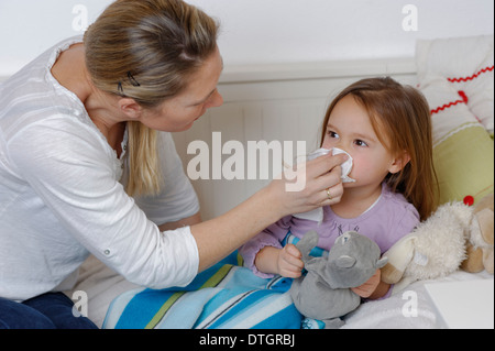 Mère en prenant soin de sa fille malade, essuyant la girl's nose, girl Lying in Bed Banque D'Images