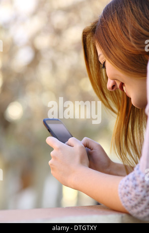 Portrait d'une femme heureuse en utilisant un téléphone intelligent avec un fond chaleur Banque D'Images