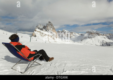 Homme assis dans une chaise longue sur une piste de ski, Massif du Sella, Dolomites, Tyrol du Sud, Italie Banque D'Images