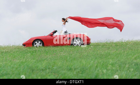 Femme dans un cabriolet laisser un linge rouge voletant dans le vent, Allemagne Banque D'Images