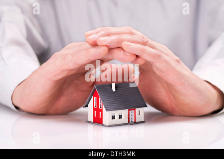 Deux mains étaient de façon protectrice autour d'une maison. Banque D'Images