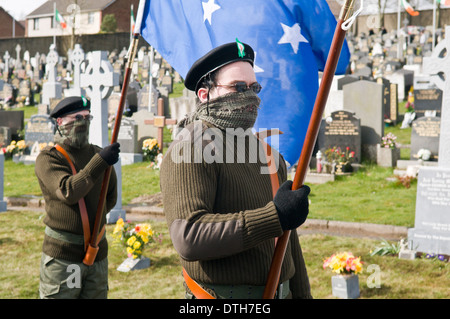 Deux hommes vêtus d'uniformes paramilitaires de l'IRA porter les drapeaux à Derry Cemetery Banque D'Images