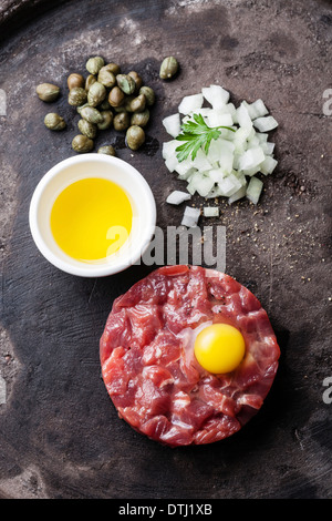 Tartare de boeuf aux câpres et oignons frais sur fond sombre Banque D'Images