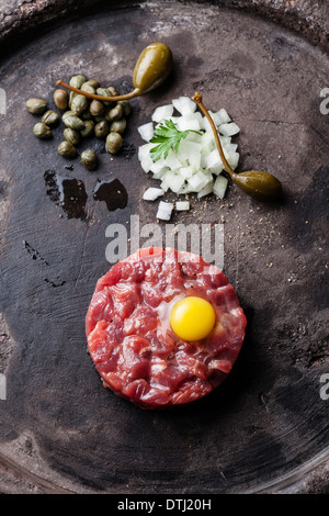 Tartare de boeuf aux câpres et oignons frais sur fond sombre Banque D'Images