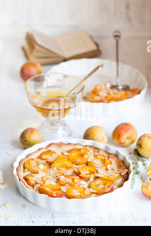 Le petit-déjeuner composé de Tarte aux abricots aux amandes, abricots frais et miel sur table en bois blanc Banque D'Images