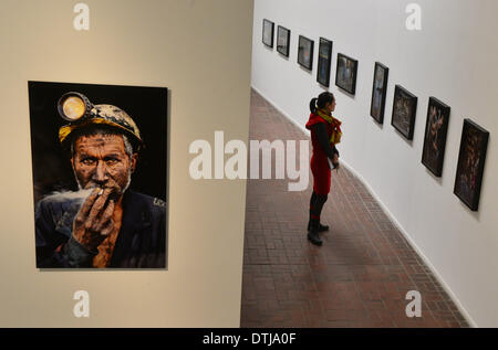 Erfurt, Allemagne. Feb 19, 2014. Une femme regarde les photographies de Steve McCurry, lors de l'exposition 'Steve McCurry' avec la photographie rétrospective "fumer Mineur de Charbon' sur la photo à gauche au musée Kunsthalle Erfurt à Erfurt, Allemagne, le 19 février 2014. La retropective de l'agence Magnum Photos présente 120 photographies prises entre 1980 et 2012. L'exposition durera du 21 février au 22 avril. Photo : MARTIN SCHUTT/dpa/Alamy Live News Banque D'Images