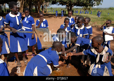 Kitgum, Ouganda école de filles de l'église catholique, les filles en bleu de l'uniforme scolaire aller chercher de l'eau potable provenant de la pompe à main Banque D'Images